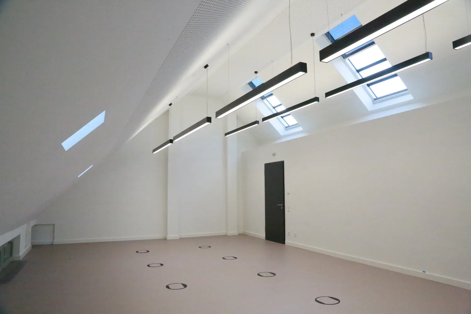 Ausgebauter Raum mit Dachschräge und einer Reihe von Dachflächenfenstern